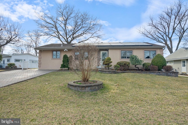 ranch-style home featuring stucco siding, solar panels, decorative driveway, and a front lawn