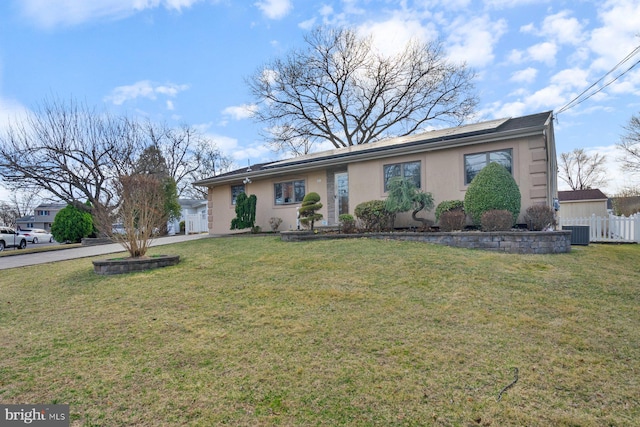 single story home featuring a front yard, fence, central AC, stucco siding, and roof mounted solar panels