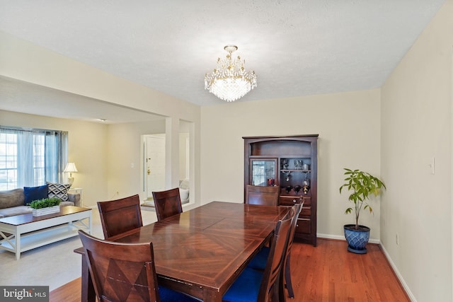 dining area featuring a chandelier, baseboards, and wood finished floors