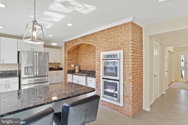 kitchen featuring light tile patterned floors, stainless steel appliances, a textured ceiling, and white cabinetry