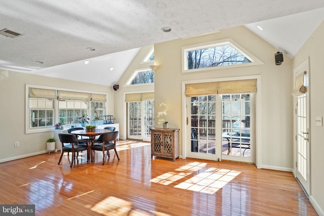 dining room featuring hardwood / wood-style floors, baseboards, visible vents, and a wealth of natural light