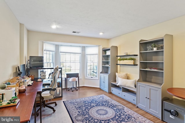 office space with visible vents, a textured ceiling, and wood finished floors