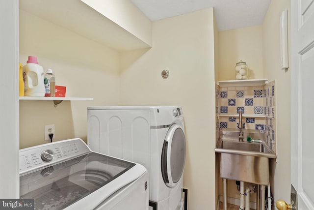 washroom with laundry area, washing machine and dryer, and a sink