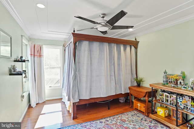 living area with crown molding, a ceiling fan, and wood finished floors