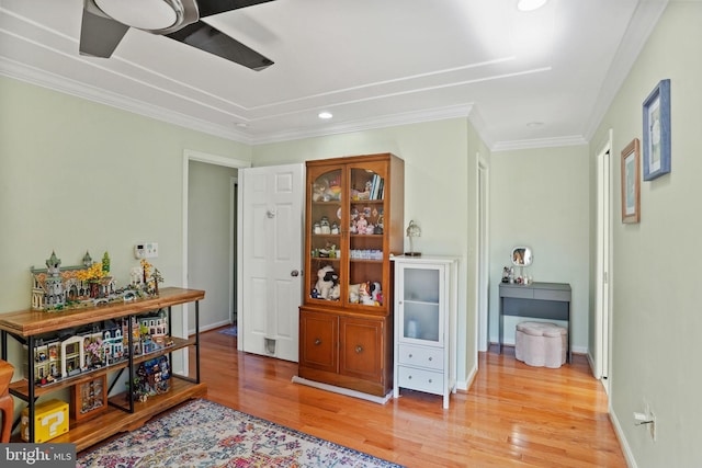 sitting room with baseboards, a ceiling fan, light wood-style flooring, and crown molding