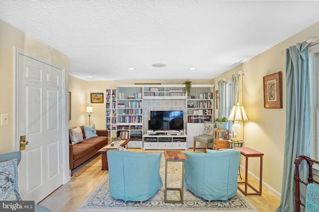 living area featuring recessed lighting, baseboards, and a textured ceiling