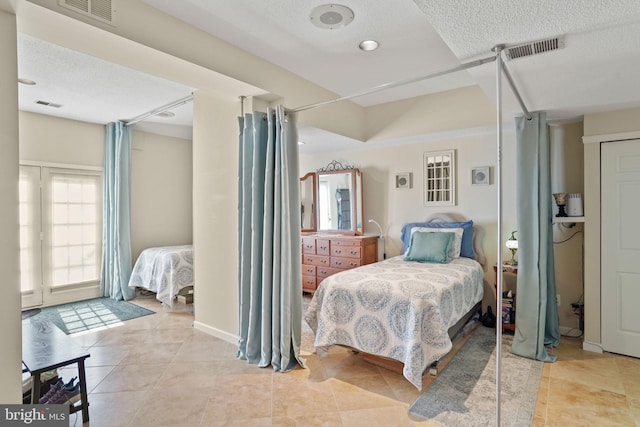 bedroom featuring light tile patterned flooring, visible vents, and a textured ceiling