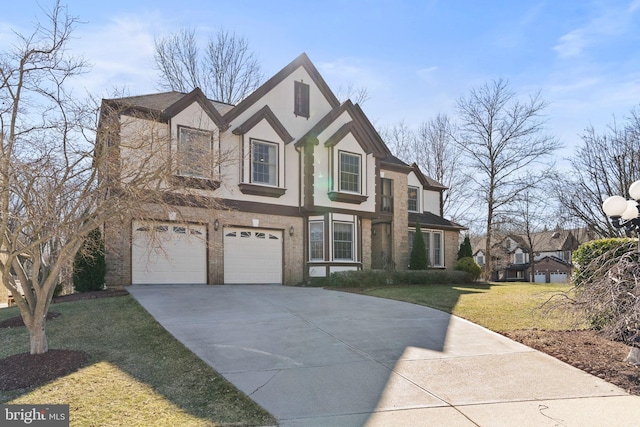 tudor house featuring brick siding, a front yard, stucco siding, a garage, and driveway