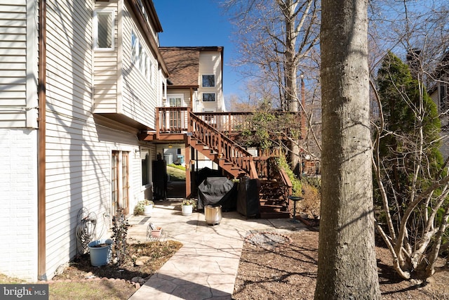 view of side of property with a wooden deck, brick siding, and stairs