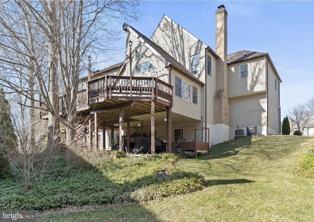 rear view of house with a deck, central AC unit, a chimney, and a yard