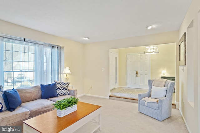 living area with baseboards, light colored carpet, and an inviting chandelier