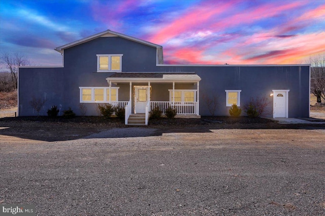 traditional home featuring covered porch and stucco siding