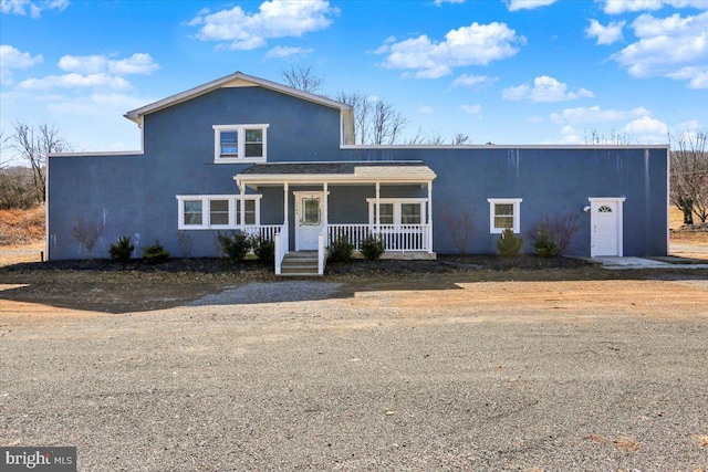 traditional-style house featuring covered porch and stucco siding