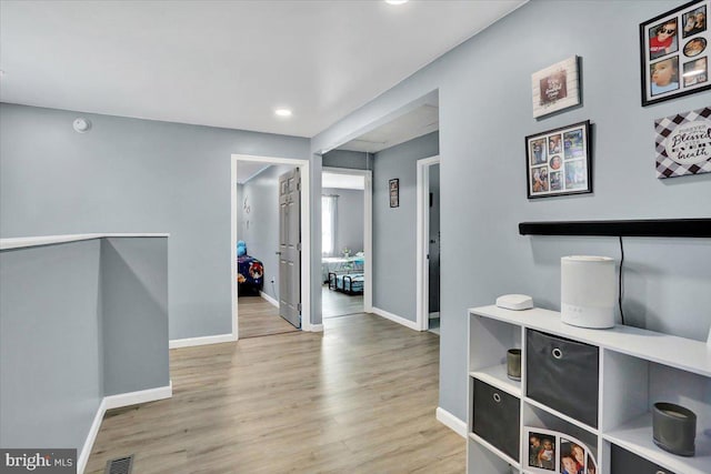 hallway with visible vents, light wood-type flooring, and baseboards