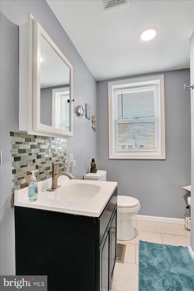 bathroom with vanity, baseboards, tile patterned floors, toilet, and tasteful backsplash