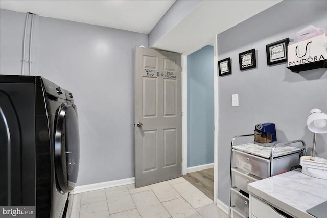 clothes washing area with washer and clothes dryer, cabinet space, and baseboards