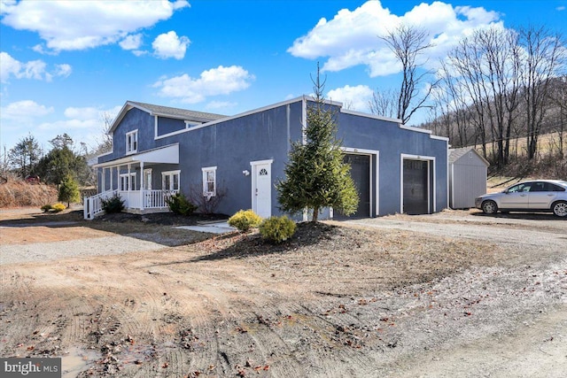 view of side of property with a porch, a garage, and stucco siding