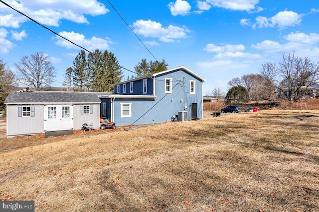 back of house with cooling unit, a lawn, and an outdoor structure