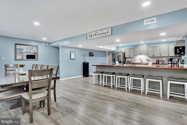 dining space featuring light wood-type flooring, visible vents, baseboards, and recessed lighting