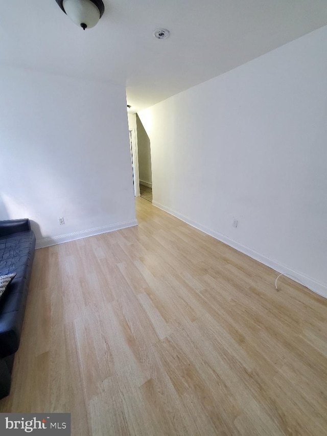 unfurnished living room featuring light wood-type flooring, baseboards, and vaulted ceiling