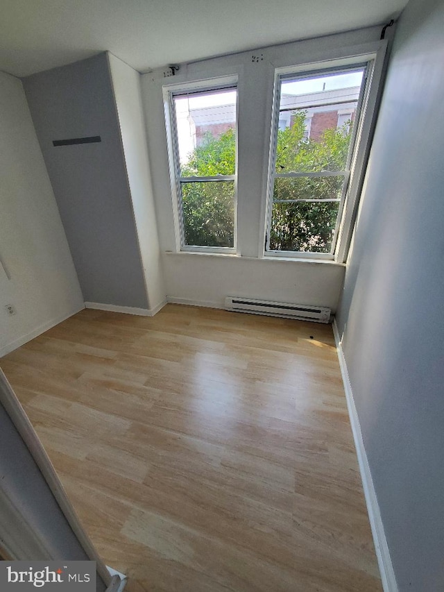 spare room with a baseboard radiator, baseboards, and wood finished floors