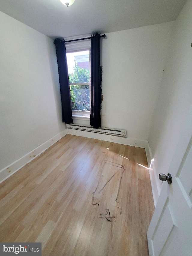 spare room featuring wood finished floors, baseboards, and a baseboard radiator