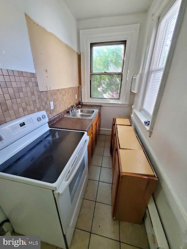 kitchen with light tile patterned floors, white electric stove, a sink, dark countertops, and tasteful backsplash