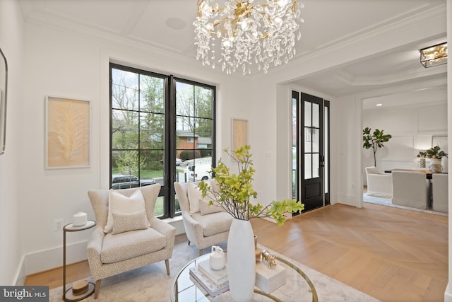 living area featuring plenty of natural light, an inviting chandelier, baseboards, and ornamental molding