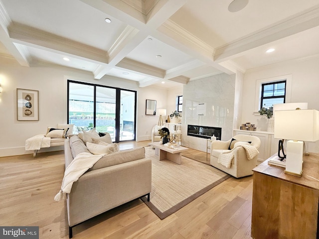 living area featuring light wood-type flooring, beam ceiling, coffered ceiling, and a healthy amount of sunlight