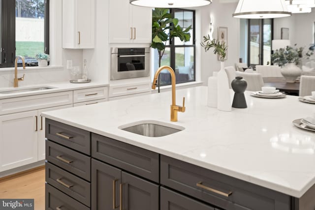 kitchen with gray cabinetry, oven, and a sink