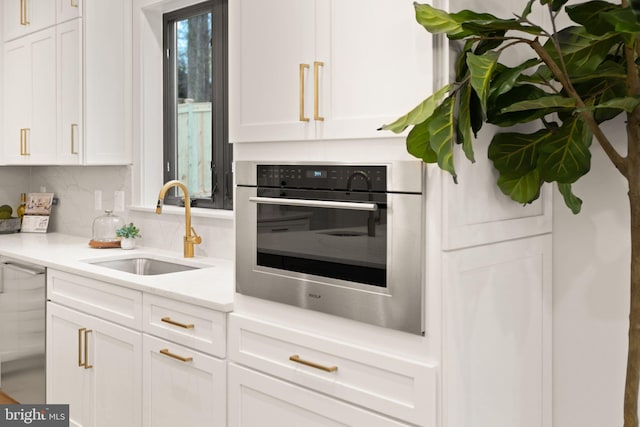 kitchen with stainless steel oven, white cabinets, and a sink