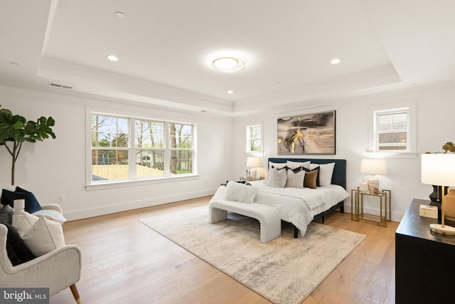 bedroom with a tray ceiling, light wood-style floors, baseboards, and ornamental molding