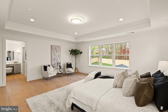 bedroom featuring a raised ceiling, light wood-style floors, and crown molding