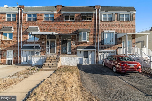 view of property with an attached garage, brick siding, and driveway