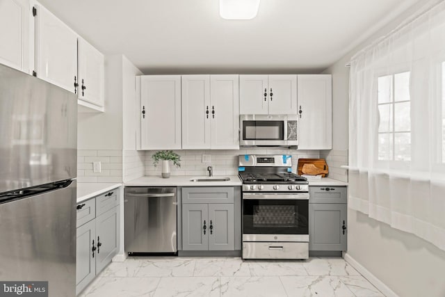 kitchen with light countertops, marble finish floor, gray cabinets, and appliances with stainless steel finishes