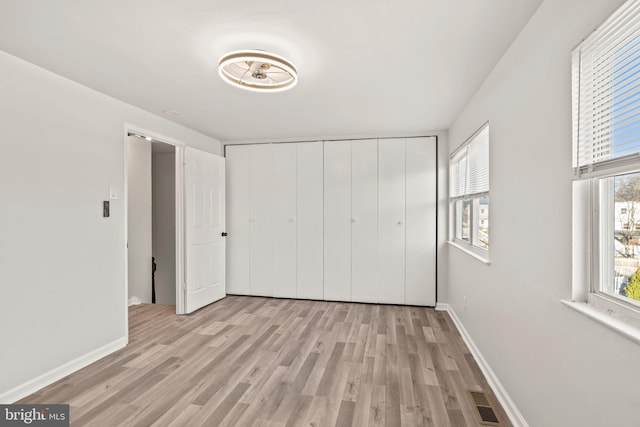 unfurnished bedroom featuring a closet, baseboards, visible vents, and light wood-style flooring