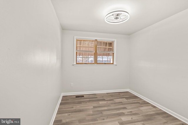 unfurnished room with visible vents, wood finished floors, and baseboards