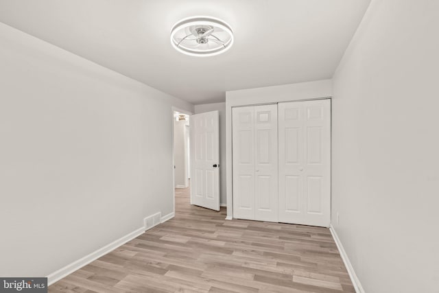 unfurnished bedroom featuring visible vents, baseboards, a closet, and light wood finished floors