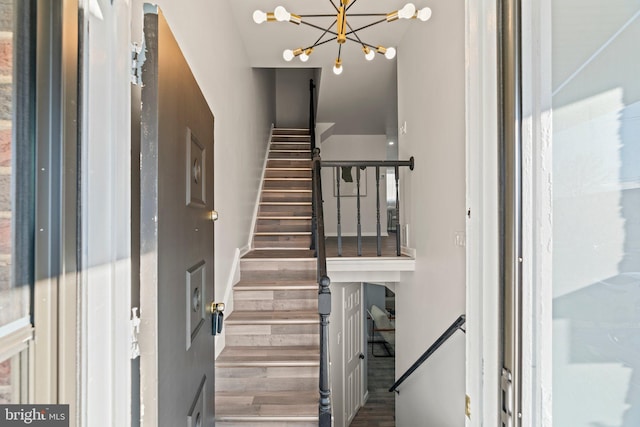 stairs with a chandelier and wood finished floors