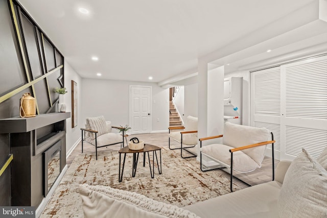 living area featuring recessed lighting, baseboards, light wood-style flooring, and stairs