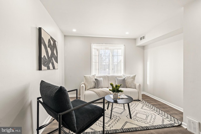 living area with visible vents, baseboards, and wood finished floors