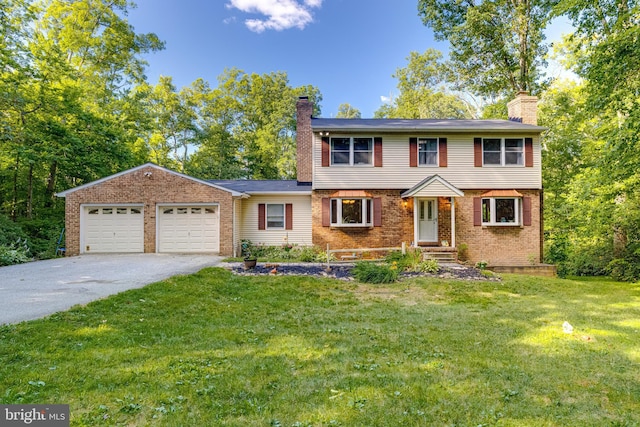 colonial house featuring driveway, a front yard, a garage, brick siding, and a chimney