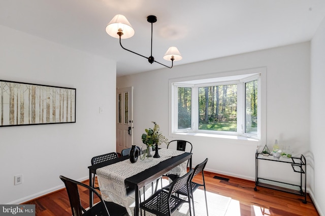 dining room featuring visible vents, baseboards, and wood finished floors