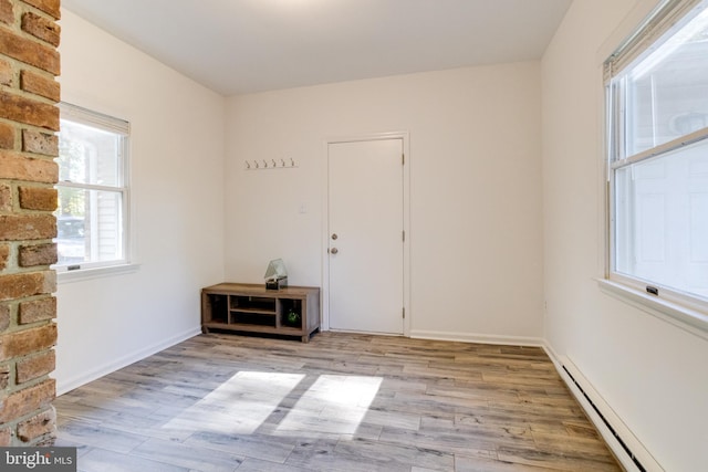 spare room featuring light wood-type flooring, baseboards, and baseboard heating