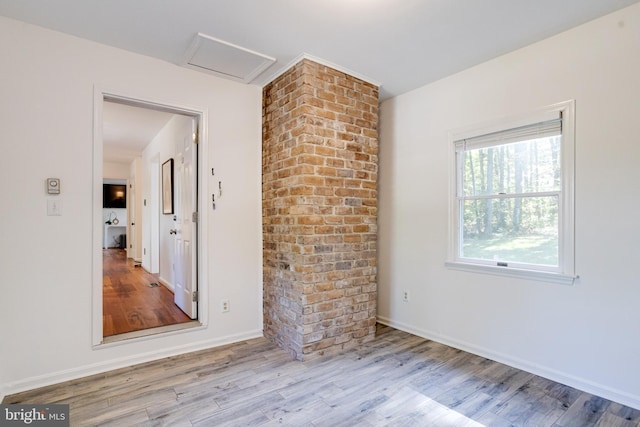 unfurnished room with baseboards, attic access, and wood finished floors