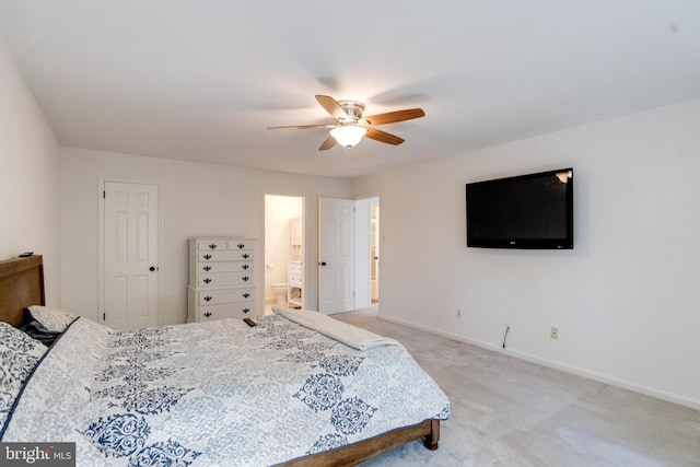 bedroom featuring baseboards, light carpet, ensuite bath, and a ceiling fan