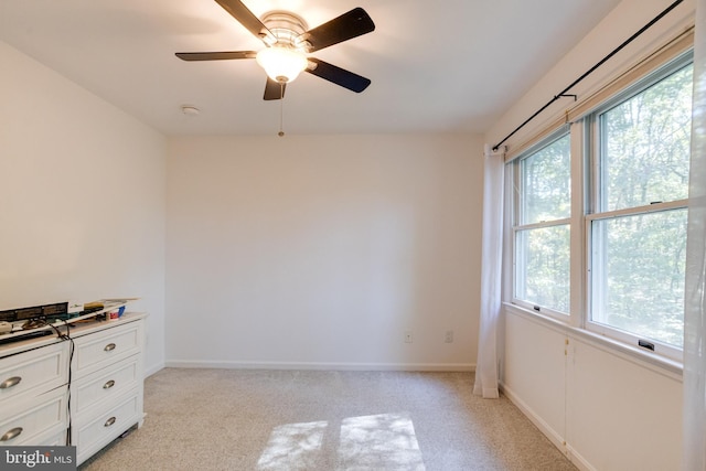 empty room featuring baseboards, light colored carpet, and a ceiling fan