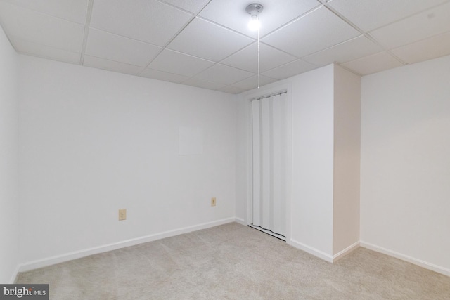 unfurnished room with a paneled ceiling, carpet floors, and baseboards