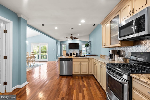 kitchen with a peninsula, a sink, appliances with stainless steel finishes, cream cabinets, and open floor plan