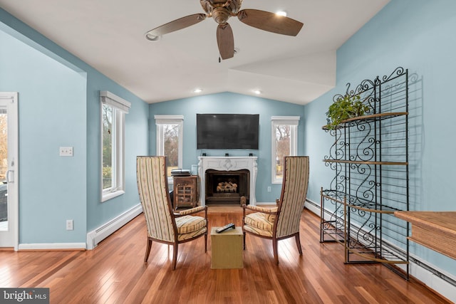 sitting room featuring a baseboard heating unit, hardwood / wood-style floors, a fireplace, baseboards, and vaulted ceiling